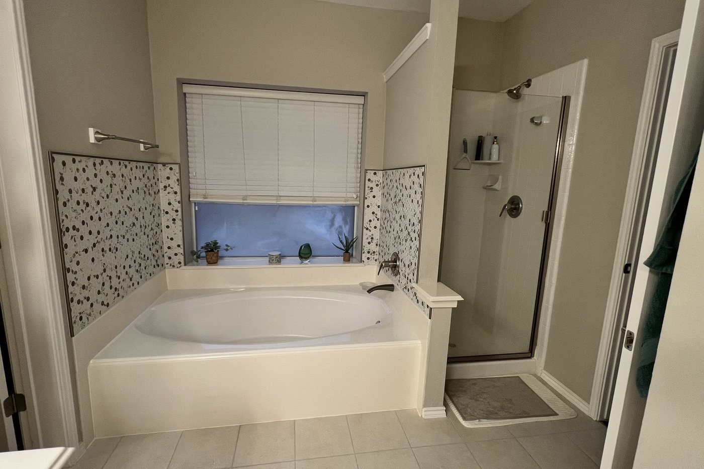 The same master bathroom before remodeling: dated drop-in tub and framed shower door