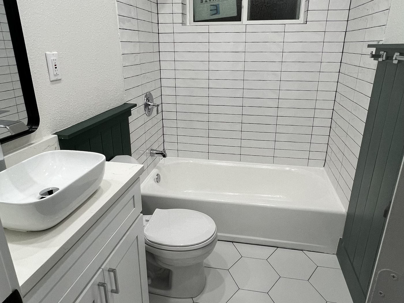 Guest bathroom with vessel sink, subway-tiled tub surround and hexagon tile floor