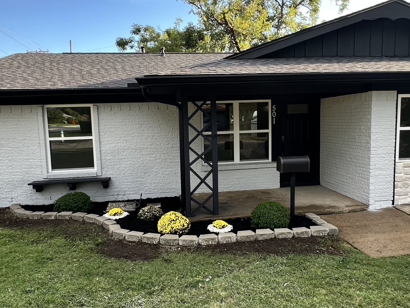 Ranch home exterior painted white brick with black trim, new columns and landscaping