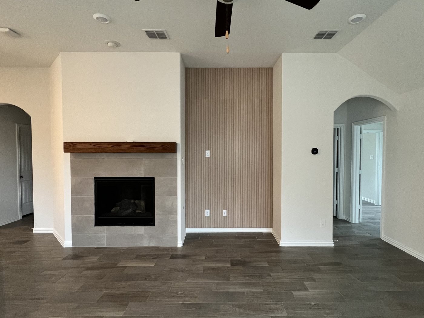 Living room with tiled fireplace, wood mantel and fluted wood accent wall